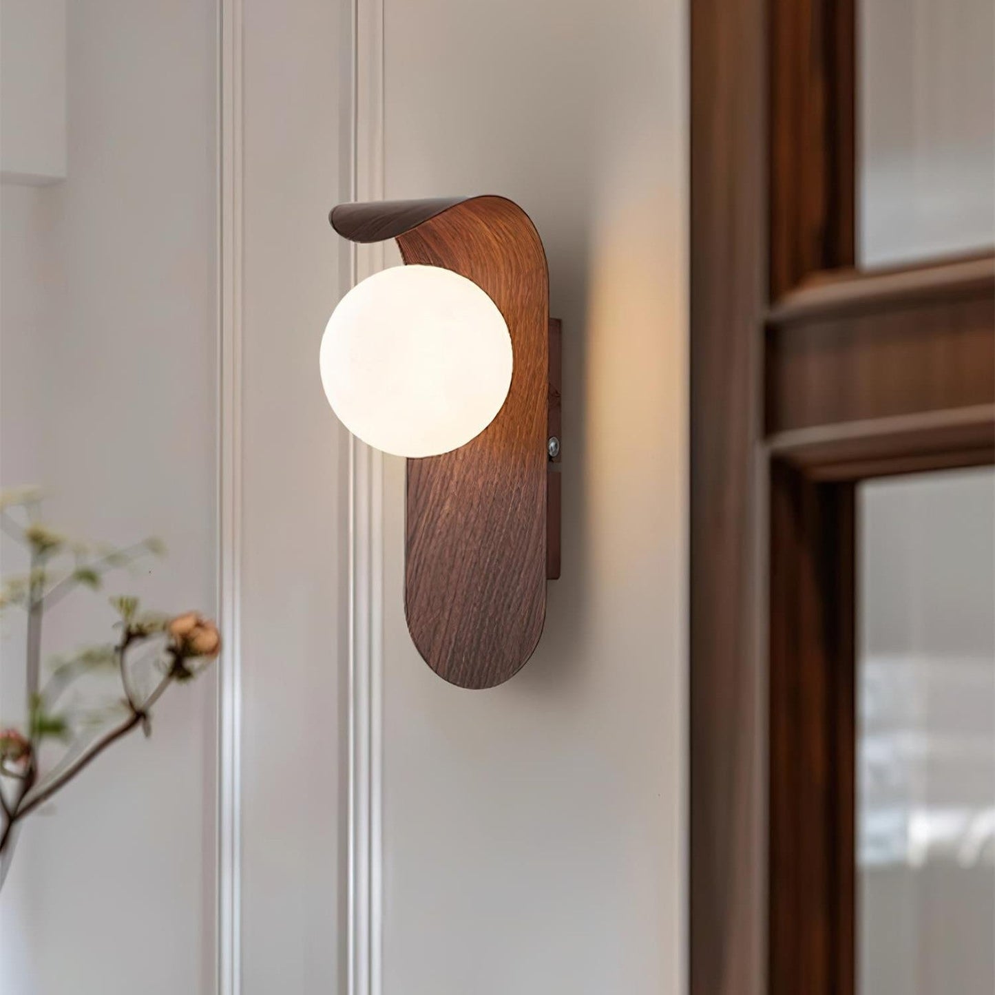 nordisk vägglampa med träinspirerad stomme och rund glasglob för varm och mjuk belysning