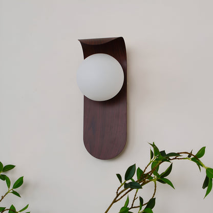 Nordisk vägglampa med träinspirerad stomme och rund glasglob för varm och mjuk belysning