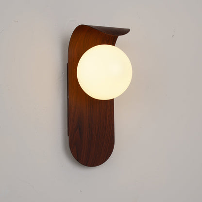 Nordisk vägglampa med träinspirerad stomme och rund glasglob för varm och mjuk belysning