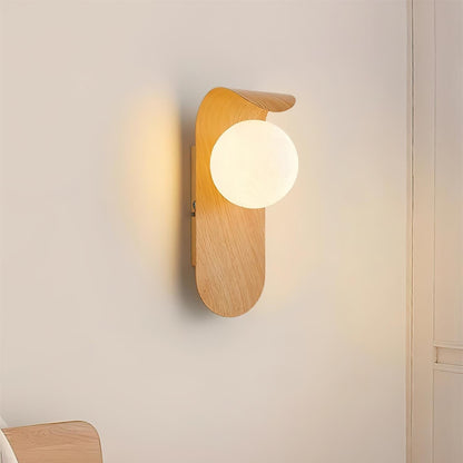Nordisk vägglampa med träinspirerad stomme och rund glasglob för varm och mjuk belysning