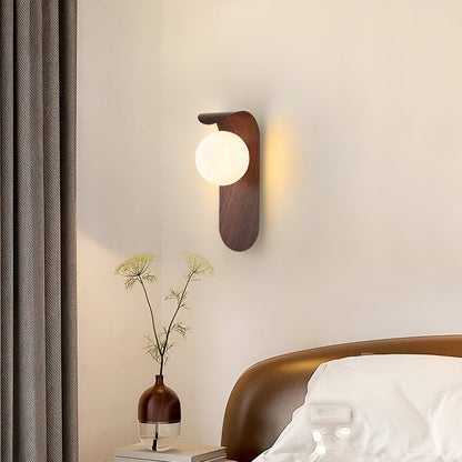 Nordisk vägglampa med träinspirerad stomme och rund glasglob för varm och mjuk belysning